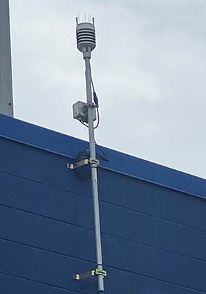 An Orion weather station mounted to the side of a building.