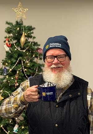 Santa in front of a Christmas Tree with CWS hat and mug