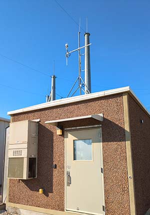 Orion weather station mounted on roof of building with blue sky in the background.