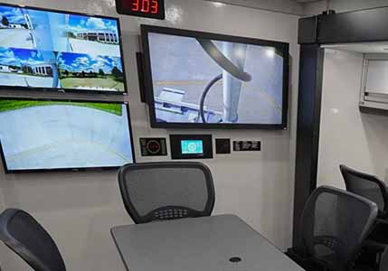 Interior of mobile command center shows weather display screen.